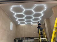 a man is working on a ladder in a room with a hexagonal ceiling